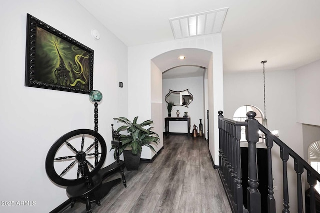 hall featuring an upstairs landing, wood finished floors, and arched walkways