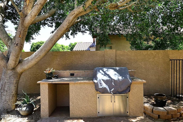 view of patio / terrace with an outdoor kitchen, fence, and a grill