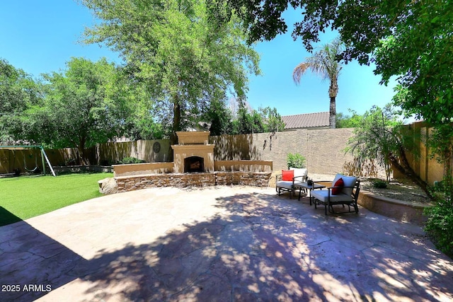 view of patio / terrace with an outdoor stone fireplace and a fenced backyard
