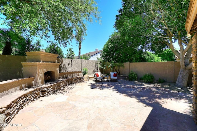 view of patio / terrace with an outdoor fireplace and a fenced backyard