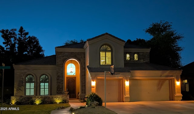 mediterranean / spanish-style home featuring stone siding, driveway, and stucco siding