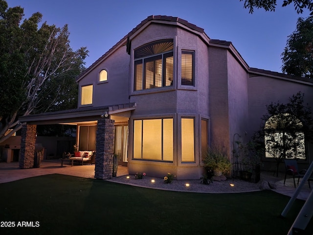 back of house with a patio area, stucco siding, and a yard