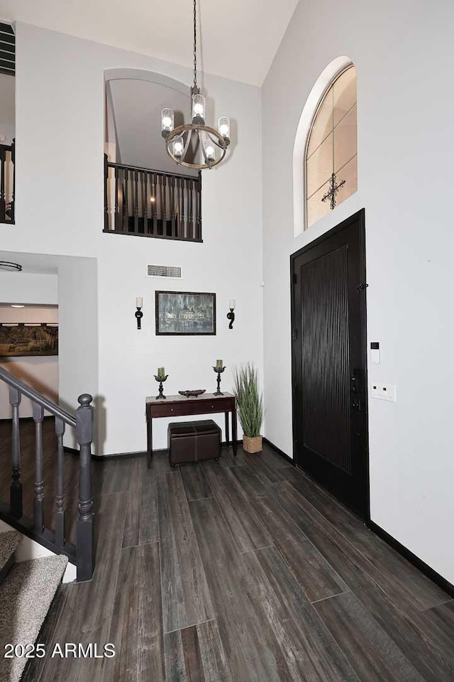 entrance foyer with wood finished floors, a high ceiling, a chandelier, stairs, and baseboards