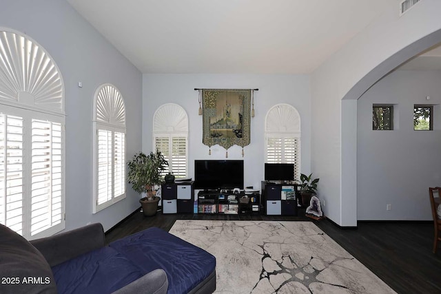 living room featuring arched walkways, healthy amount of natural light, and wood finished floors