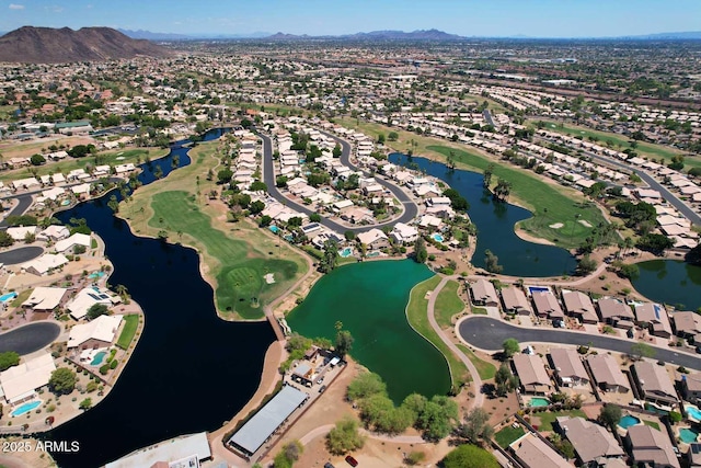 view of property location with nearby suburban area, a water and mountain view, and a golf course