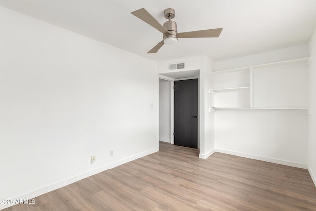 interior space featuring a ceiling fan, light wood-style flooring, visible vents, and baseboards