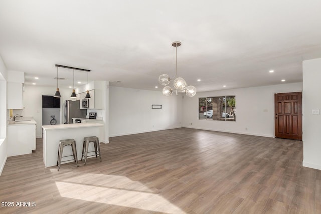 living room with light wood-style flooring, baseboards, a chandelier, and recessed lighting