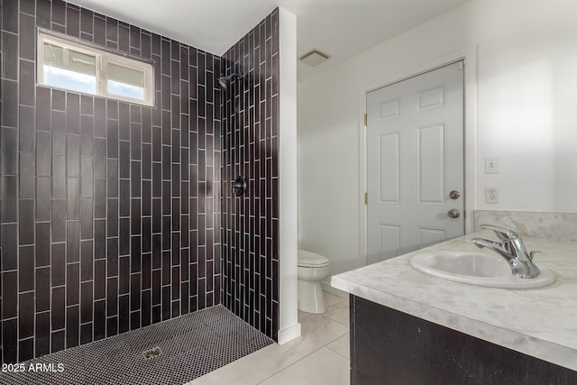 bathroom with toilet, visible vents, a tile shower, and vanity