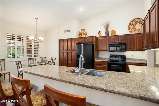 kitchen with sink, black appliances, light stone countertops, decorative light fixtures, and vaulted ceiling