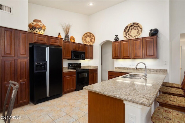 kitchen featuring black appliances, kitchen peninsula, sink, and a high ceiling