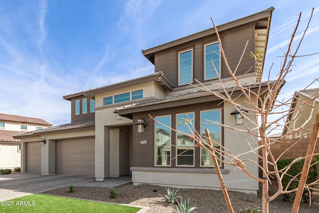 view of front of home featuring driveway, an attached garage, and stucco siding