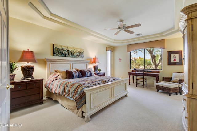 carpeted bedroom with a raised ceiling and ceiling fan