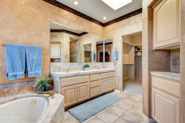 bathroom featuring vanity, a relaxing tiled tub, and tile patterned flooring