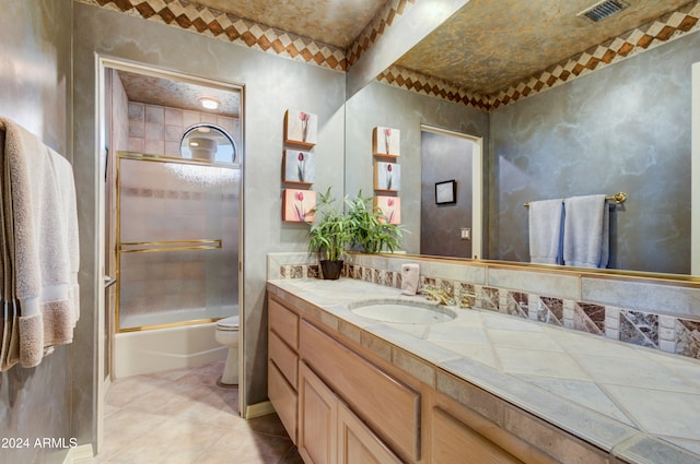 full bathroom featuring vanity, enclosed tub / shower combo, toilet, and tile patterned flooring