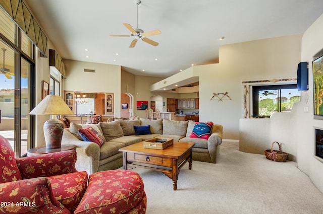 carpeted living room featuring a high ceiling and ceiling fan with notable chandelier