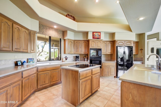 kitchen with sink, black appliances, light tile patterned flooring, and a kitchen island