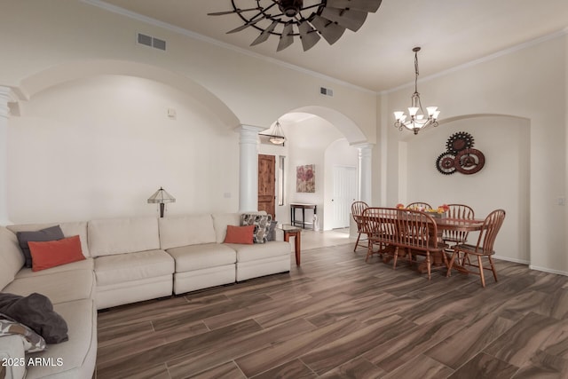 living room featuring a ceiling fan, decorative columns, visible vents, arched walkways, and ornamental molding