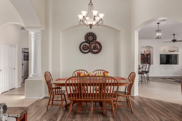 dining space with arched walkways, ornate columns, ceiling fan with notable chandelier, and wood finished floors