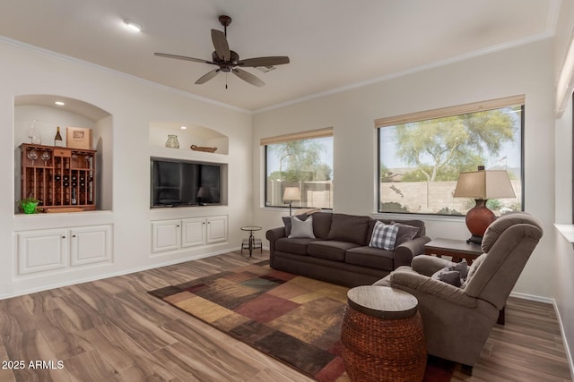 living room featuring crown molding, baseboards, ceiling fan, and wood finished floors