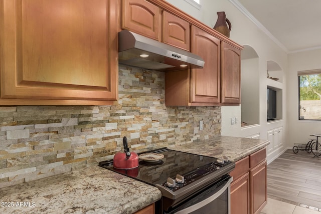 kitchen featuring crown molding, arched walkways, range with electric cooktop, backsplash, and under cabinet range hood