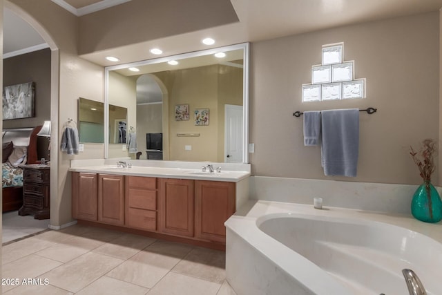 full bath with double vanity, a garden tub, a sink, tile patterned floors, and ornamental molding