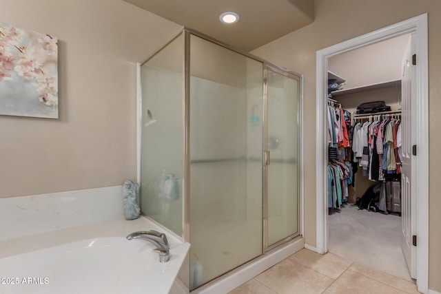 bathroom with tile patterned flooring, a garden tub, a stall shower, and a spacious closet