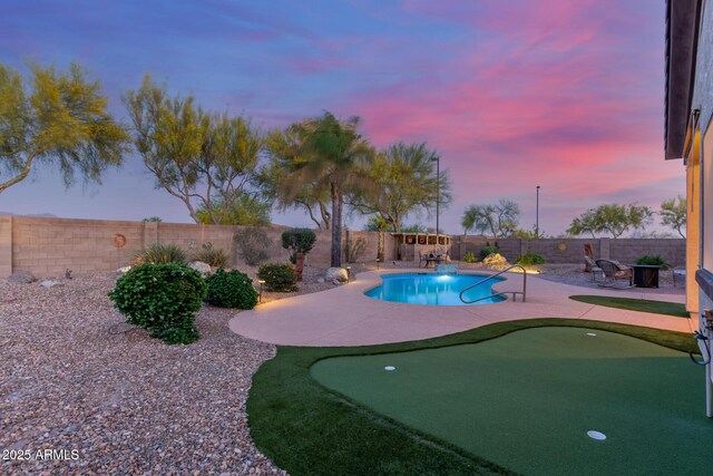 pool at dusk with a fenced backyard, a fenced in pool, and a patio