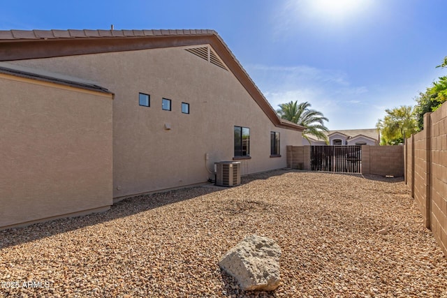 rear view of property with central AC, fence, a gate, and stucco siding