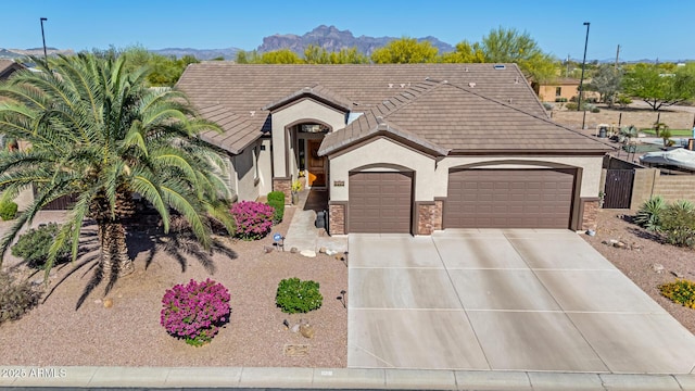 view of front of house with a garage, stucco siding, a tiled roof, a mountain view, and driveway