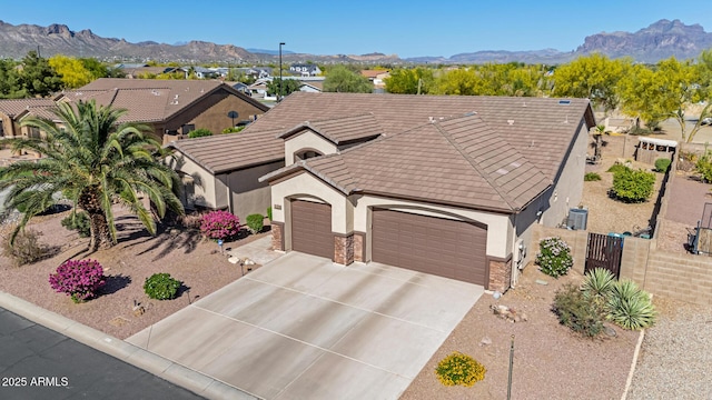 view of front of property featuring a mountain view, fence private yard, stone siding, and stucco siding