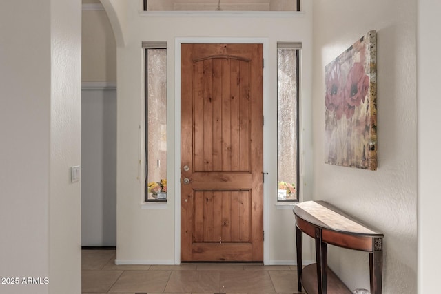 tiled entryway featuring baseboards and arched walkways