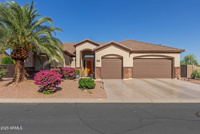mediterranean / spanish-style home featuring an attached garage, stucco siding, driveway, and stone siding