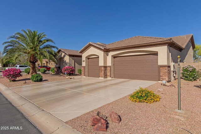 mediterranean / spanish-style home with stone siding, stucco siding, concrete driveway, an attached garage, and a tile roof