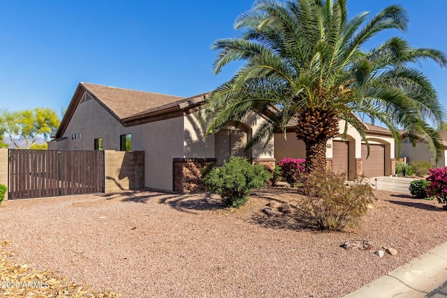 view of home's exterior with fence, stucco siding, a gate, an attached garage, and driveway