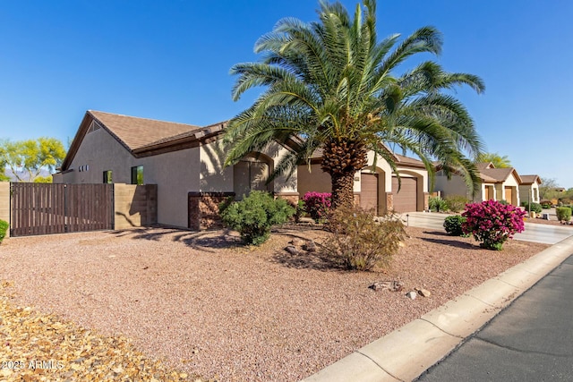 view of front of house with driveway, a gate, fence, an attached garage, and stucco siding