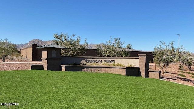 community / neighborhood sign featuring a mountain view and a yard