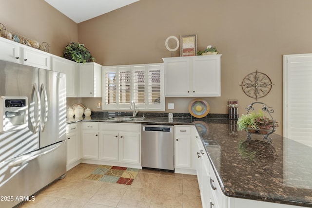 kitchen featuring light tile patterned flooring, sink, white cabinetry, dark stone countertops, and stainless steel appliances