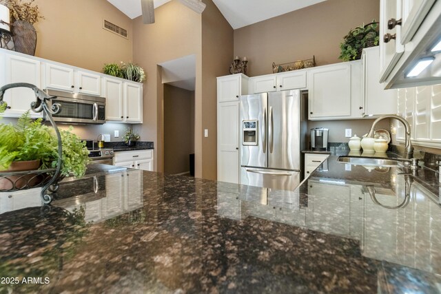 kitchen featuring stainless steel appliances, white cabinetry, sink, and dark stone countertops