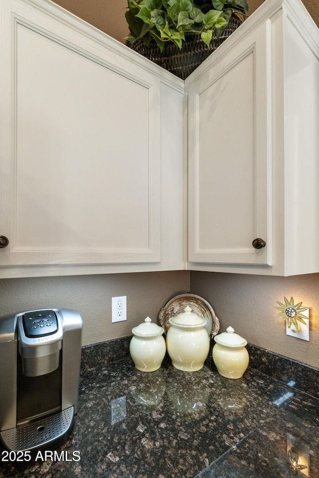 interior details with white cabinetry and dark stone counters