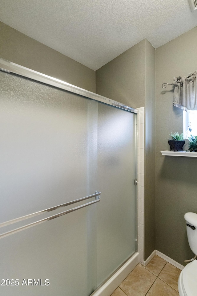 bathroom with tile patterned flooring, an enclosed shower, a textured ceiling, and toilet