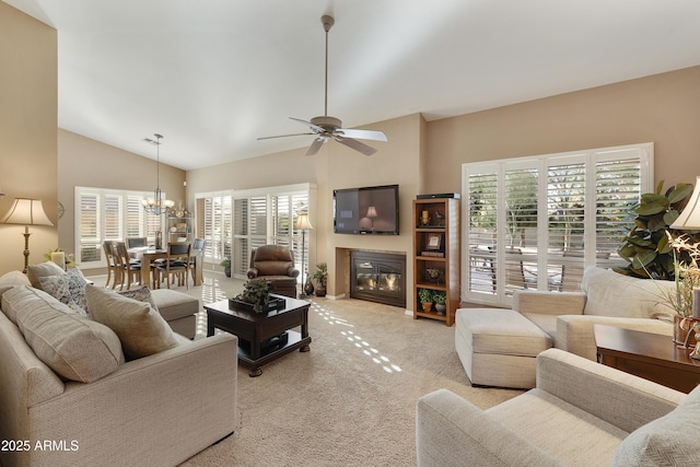 living room featuring light colored carpet, lofted ceiling, and ceiling fan with notable chandelier