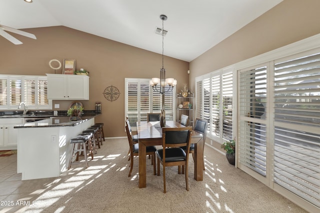 tiled dining room with ceiling fan with notable chandelier, high vaulted ceiling, and sink