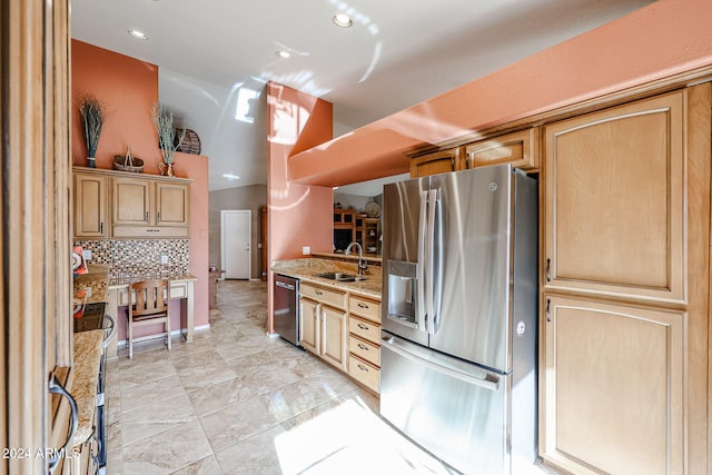 kitchen with light brown cabinets, sink, decorative backsplash, light stone countertops, and stainless steel appliances