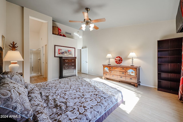 bedroom with light wood-type flooring, a towering ceiling, connected bathroom, and ceiling fan