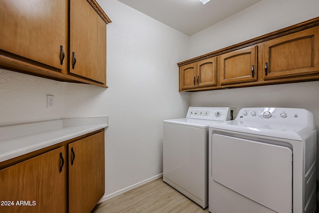 laundry area featuring cabinets, separate washer and dryer, and light hardwood / wood-style flooring