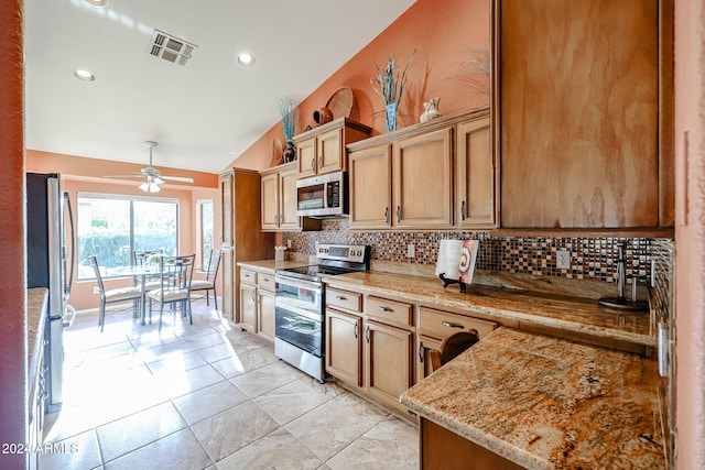 kitchen featuring ceiling fan, stainless steel appliances, light stone counters, vaulted ceiling, and decorative backsplash