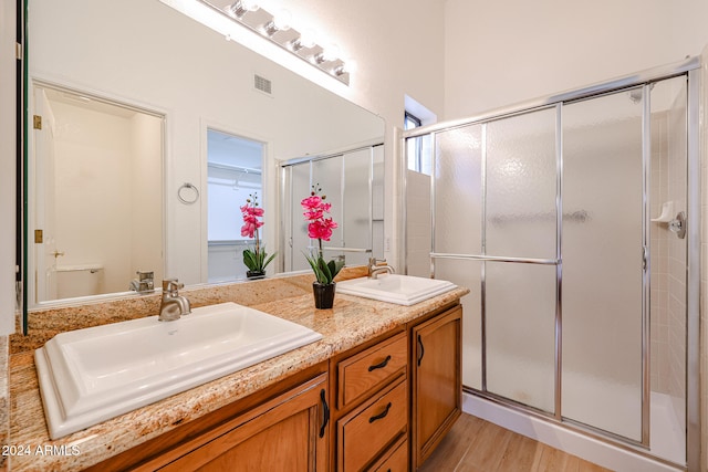 bathroom featuring hardwood / wood-style floors, vanity, a shower with shower door, and toilet