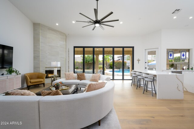 living room featuring a fireplace, light hardwood / wood-style flooring, and ceiling fan