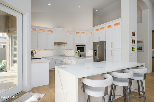 kitchen with white cabinets, a center island, stainless steel appliances, and light hardwood / wood-style flooring