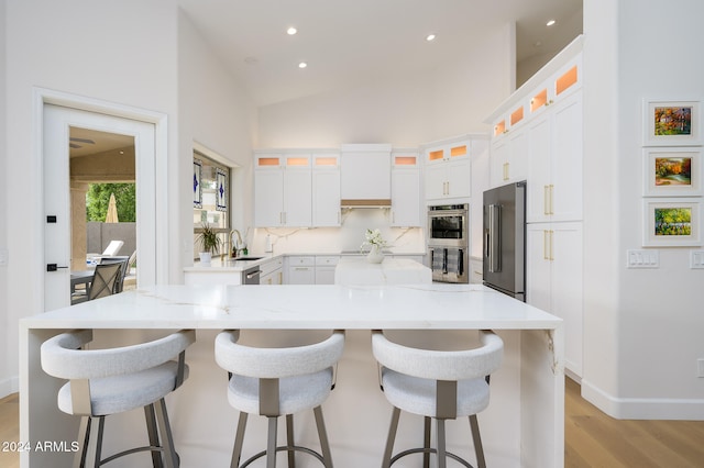 kitchen featuring appliances with stainless steel finishes, custom exhaust hood, vaulted ceiling, a spacious island, and white cabinets